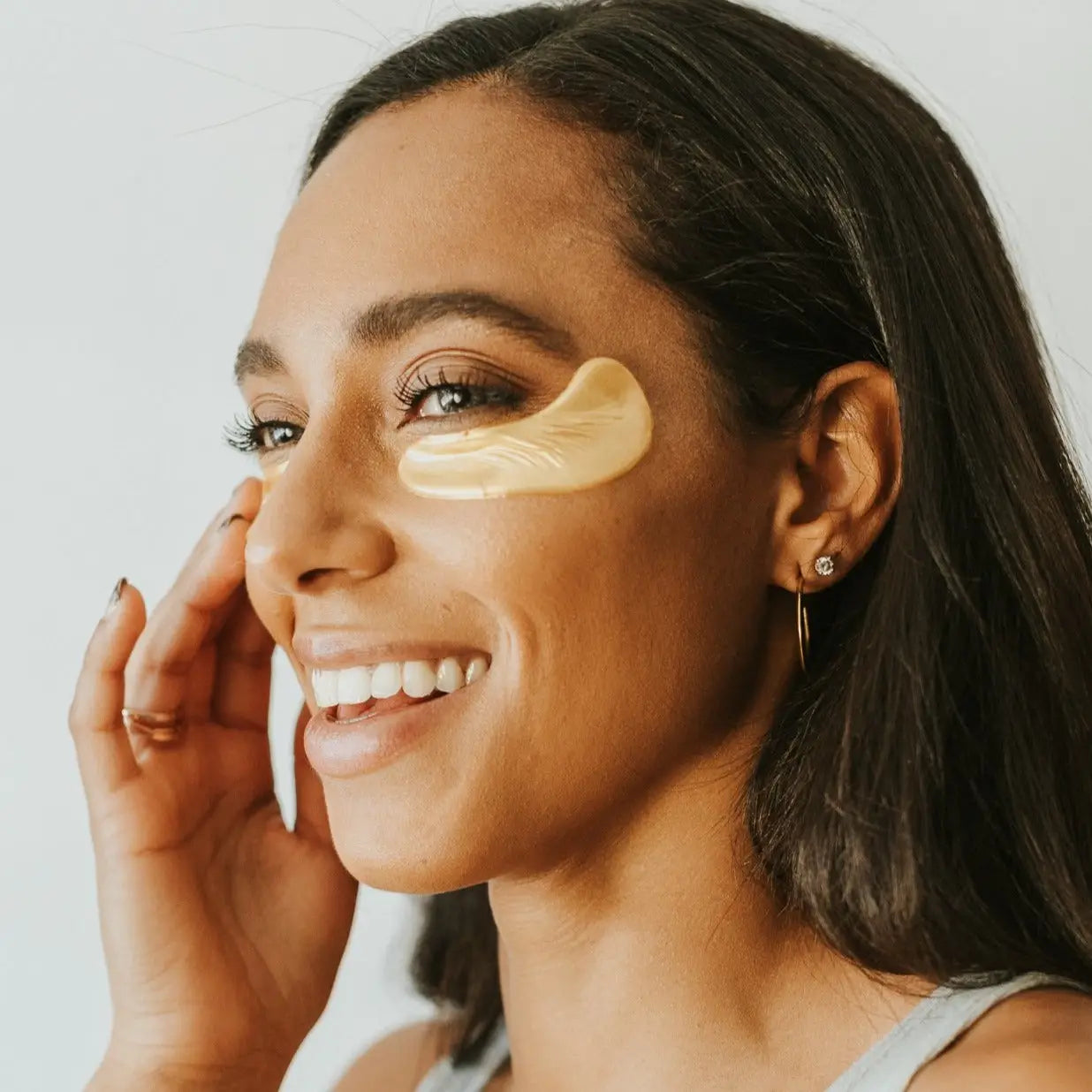 Woman Smiling with Gold eye mask on her under eyes